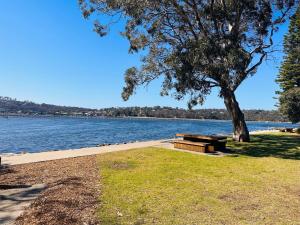 una mesa de picnic bajo un árbol junto a un lago en Fishpen Holiday Units, en Merimbula