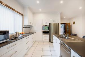 a kitchen with white cabinets and a stainless steel refrigerator at Tangerine - Pet Friendly - 3 Mins Walk to Beach in Sanctuary Point