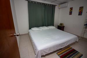 a bedroom with a white bed with a green curtain at Hospedaje Casa Pachi en Cartagena de Indias in Cartagena de Indias