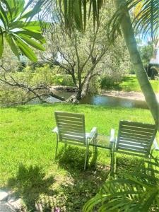 2 bancs du parc assis dans l'herbe près d'un étang dans l'établissement Stylish Coastal Townhome in Jupiter, à Jupiter