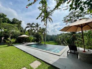 una piscina con 2 sillas y una sombrilla en The Papas Villas en Tegalalang