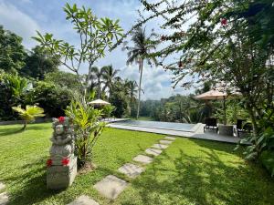 a resort yard with a swimming pool and a garden at The Papas Villas in Tegalalang