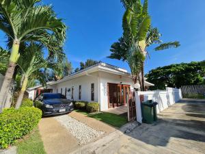 Un coche aparcado delante de una casa con palmeras. en ทิวาพูลวิลล่า หัวหิน Thiva Pool Villa Hua Hin, en Hua Hin