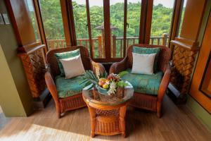 a porch with two chairs and a table with flowers on it at Highland Bali Villas, Resort and Spa 