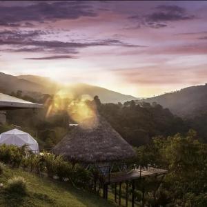 a view of a mountain with a hut and the sunrise at Glamping San Luis in San Luis