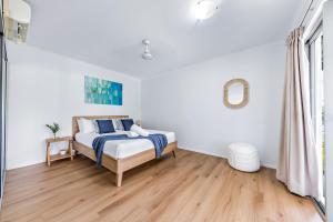 a white bedroom with a bed and a wooden floor at Casa Ava Airlie in Airlie Beach
