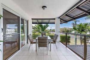 uma sala de jantar com uma mesa e cadeiras numa varanda em Casa Ava Airlie em Airlie Beach