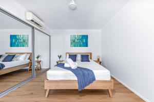a bedroom with two beds and a mirror at Casa Ava Airlie in Airlie Beach