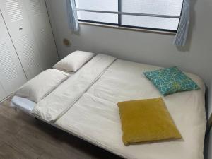 a bed with white sheets and pillows and a window at 江元浅草 in Tokyo