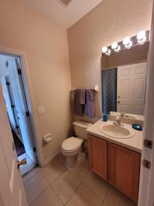 a bathroom with a toilet and a sink and a mirror at Townhouse in Regal Palms Resort, Amenities, Pool & lazy river, Near Disney, Orlando in Davenport