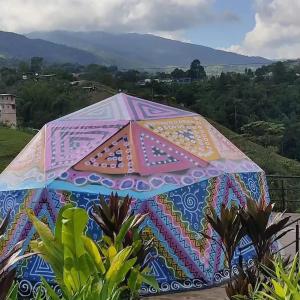 a large colorful umbrella sitting in a garden at Glamping San Luis in San Luis