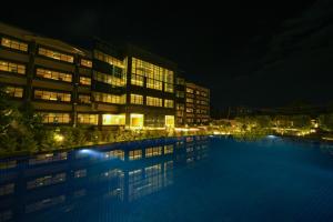 a swimming pool in front of a building at night at Hotel CN Windsor Chikmagaluru in Chikmagalūr