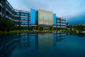 a building with a reflection in a pool of water at Hotel CN Windsor Chikmagaluru in Chikmagalūr