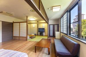 Cette chambre comprend un canapé, une table et des fenêtres. dans l'établissement KAMENOI HOTEL Tazawako, à Senboku