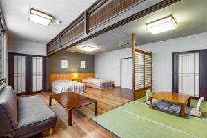 a room with two beds and a couch and a table at KAMENOI HOTEL Tazawako in Senboku