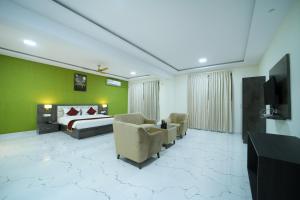 a bedroom with a bed and chairs and a television at Hotel CN Windsor Chikmagaluru in Chikmagalūr