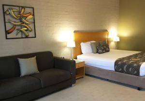 a hotel room with a bed and a couch at Blazing Stump Motel & Suites in Wodonga