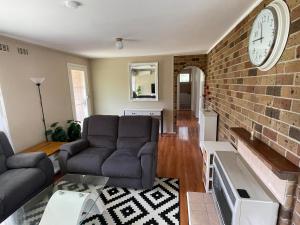 ein Wohnzimmer mit einer Couch und einer Ziegelwand in der Unterkunft Canberra Hospital Locum Welcome - Two Beds House in Harman