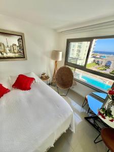 a bedroom with a bed with red pillows and a pool at Imperialeluxuryapartment in Punta del Este