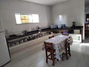 una cocina con mesa y sillas. en Casa Tropicana (2º andar), en Flecheiras