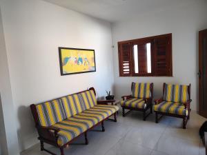 uma sala de estar com duas cadeiras e um sofá em Casa Tropicana (2º andar) em Flecheiras