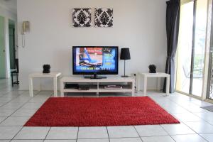 sala de estar con TV y alfombra roja en Alexander Beachfront Apartments, en Hervey Bay