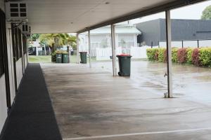 an empty hallway of a building with three trash cans at Porky's Motel Rockhampton in Rockhampton