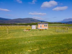 una casetta in un campo con montagne sullo sfondo di Warburton Tiny House - Tiny Stays a Yarra Junction Altre 9 foto