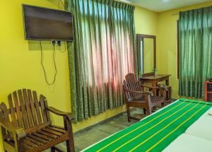 a room with a bed and two chairs and a flat screen tv at Yala Golden Wild in Tissamaharama
