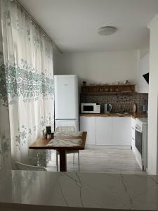 a kitchen with a table and a white refrigerator at Apartament27 in Almaty