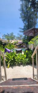un patio con sillas, una sombrilla y una piscina en Purple Beach - Maïthélia - Gili Air, en Gili Air