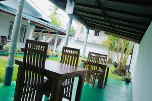een houten tafel en stoelen op een veranda bij Hikkaduwa White Villa near to beach with 3 bedroom in Galle