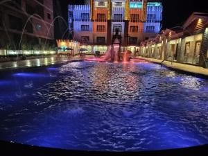 a pool of blue water in a city at night at THE RATH INNS in Mandarmoni