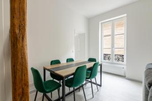 a dining room with a table and green chairs at Luxurious 2 Bedroom Avenue des Champs-Élysées Saint-Philippe du Roule Free Netflix in Paris