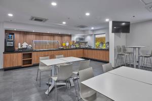 a room with tables and chairs and a kitchen at City Express by Marriott Monterrey Aeropuerto in Monterrey