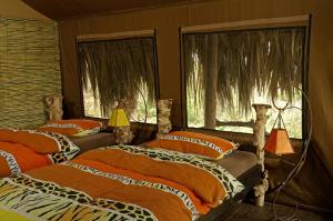 two beds in a room with two windows at Crater Forest Tented Lodge in Karatu