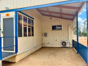 Cette petite maison dispose d'une porte bleue et d'un ventilateur. dans l'établissement West View Caravanpark, à Dubbo