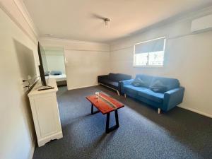- un salon avec un canapé bleu et une table dans l'établissement West View Caravanpark, à Dubbo
