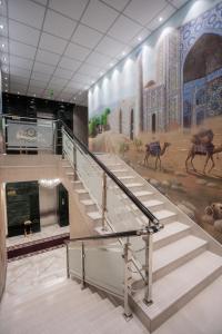una escalera en un edificio con una pintura en la pared en Hotel Arhan Palace, en Samarkand