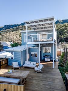 a blue house with a deck with a table and chairs at The Terrace @ Scarborough NSW 