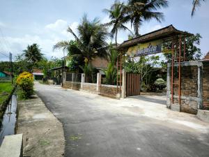 pusta ulica z budynkiem i palmami w obiekcie Puri Swantari Javanese Home Stay w mieście Sleman