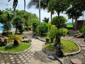 a garden with palm trees and a walkway at Puri Swantari Javanese Home Stay in Sleman