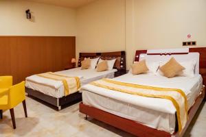 Cette chambre d'hôtel comprend deux lits et une chaise jaune. dans l'établissement Ekefaru Inn, à Viligili
