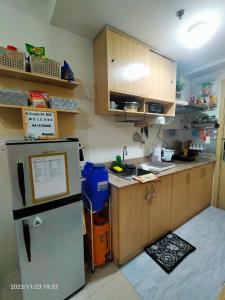 Elle comprend une petite cuisine équipée d'un réfrigérateur et de placards en bois. dans l'établissement Condo by Bambie near NAIA airport, à Manille
