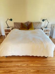 1 cama blanca con 2 lámparas en 2 mesas en Willdenowia Guestsuite at Waboom Family Farm, en Stanford