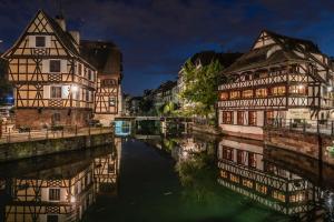 un grupo de edificios junto a un río por la noche en Appartement neuf haut standing - jacuzzi à Strasbourg, en Schiltigheim