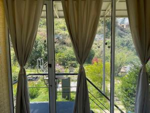 una ventana abierta con cortinas y vistas al jardín en Nhà Trong Sương Đà Lạt en Dalat