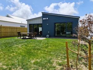 uma casa azul com uma mesa num quintal em Sunshine Haven - New 3-Bedroom 4-Beds in Paraparaumu em Paraparaumu