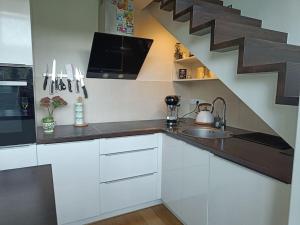 een keuken met witte kasten, een wastafel en een trap bij River Vilnele View Studio in Vilnius