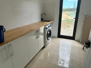 cocina con lavadora y ventana en Port Lane Lower Apartment, en Geographe